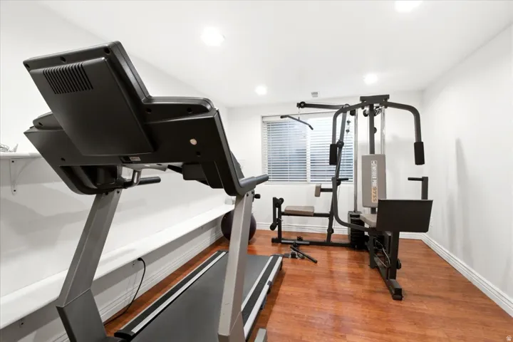 Recessed lighting illuminates the space, featuring wood-finish flooring and white baseboards