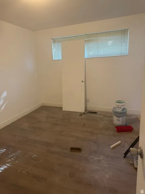 Wood-finish flooring with crisp white baseboards, a flush-mount ceiling light, and a horizontal window with blinds