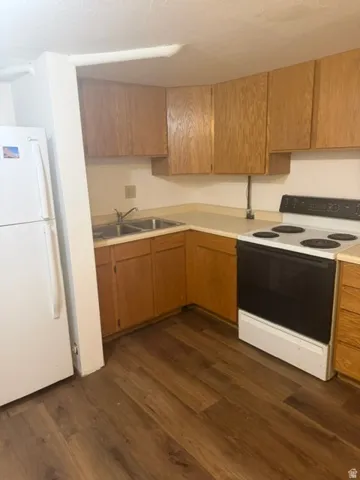 Kitchen featuring wood-finish flooring, a double basin stainless steel sink, and light wood cabinetry with upper and lower storage