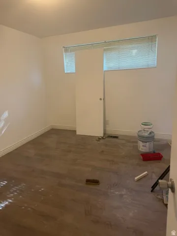 Wood-finish flooring with crisp white baseboards, a flush-mount ceiling light, and a horizontal window with blinds