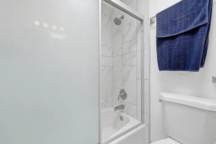 Bathtub with tile surround, glass shower enclosure, and brushed nickel fixtures