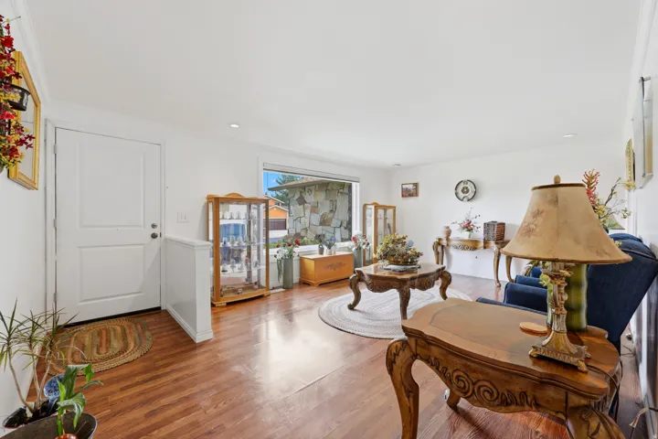 Wood-finish flooring throughout, white interior walls, and a prominent front entry door