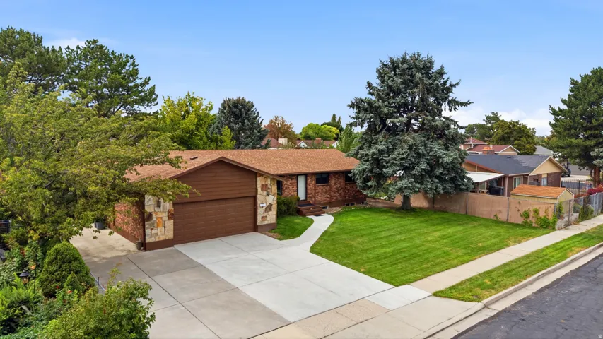 Split-level residence featuring a concrete driveway, attached two-car garage, and a lush front lawn
