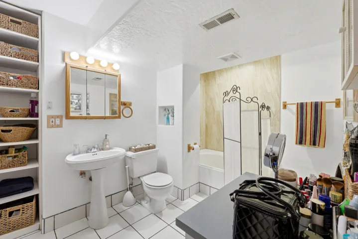 White tiled flooring and a pedestal sink