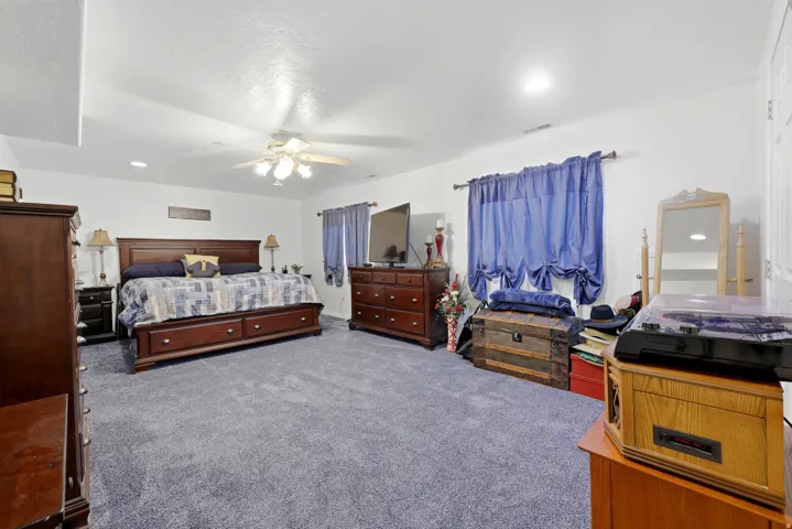 Spacious carpeted room featuring a ceiling fan with integrated lighting and recessed ceiling lights