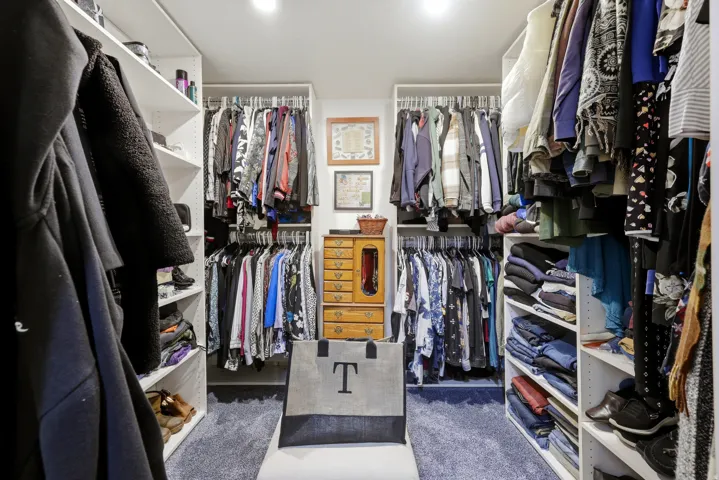 Custom closet system with built-in shelving, multiple hanging rods, and integrated lighting