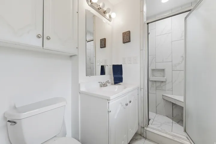 White vanity with integrated sink, mirror, and overhead light fixture