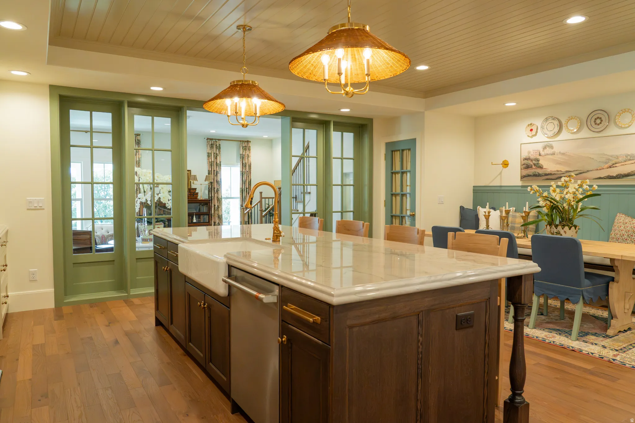 Central kitchen island with a light-toned countertop, farmhouse sink, and integrated dishwasher
