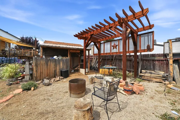 Gravel hardscaping with a wood pergola, wood fencing, and a detached wood shed