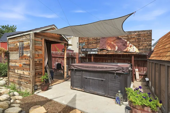 Concrete patio featuring a built-in spa with cover, adjacent to a wood-sided shed with an open entry