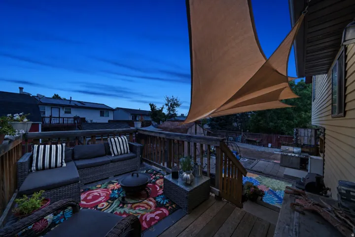 Expansive outdoor deck with wood railing, sail shade, and a built-in outdoor seating area
