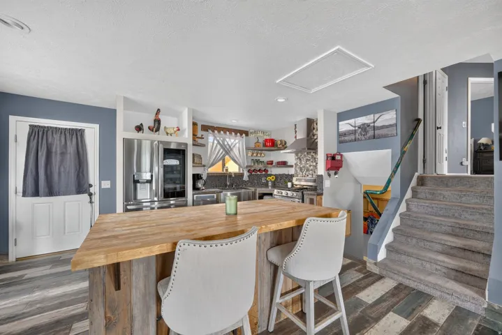 Kitchen with a wood-finish island, stainless steel refrigerator, and built-in shelving