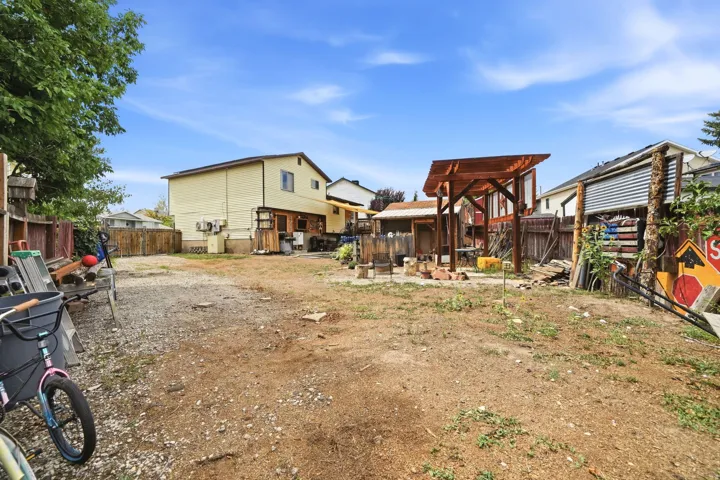 Expansive backyard with a wooden pergola structure and a fenced perimeter