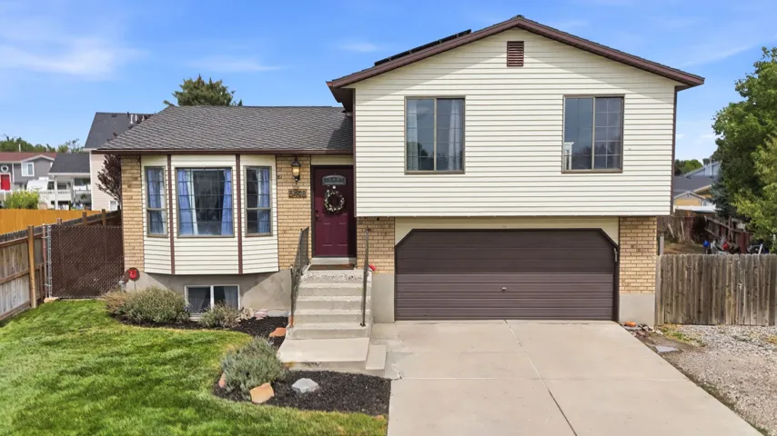 Split-level residence featuring a brick and siding exterior, two-car garage, and a concrete driveway