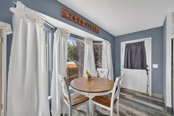 Bay window with white trim, wood-finish flooring, and a paneled white door