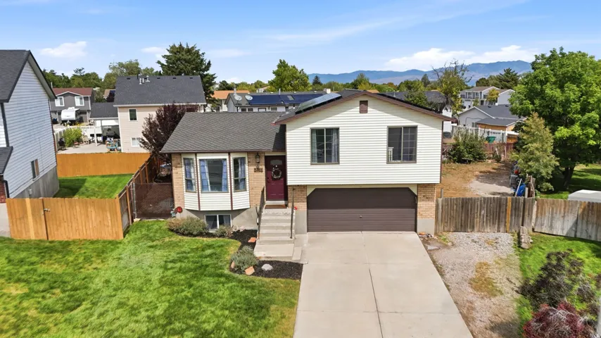 Split-level home featuring a brick and siding exterior, an attached garage, a bay window, and a concrete driveway