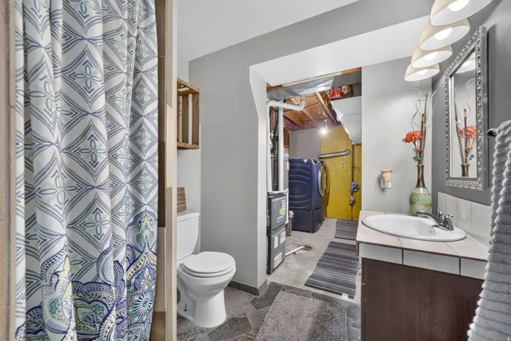 Vanity with a tiled countertop and integrated sink, framed mirror, and pendant lighting