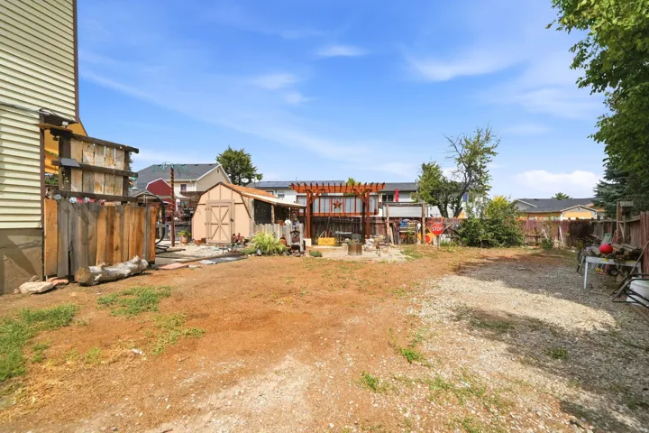 Expansive outdoor space featuring a detached shed, a pergola structure, and a wood privacy fence