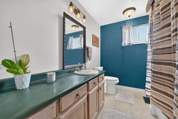 Vanity with an integrated sink, framed mirror, wall-mounted light fixture, and a window for natural light