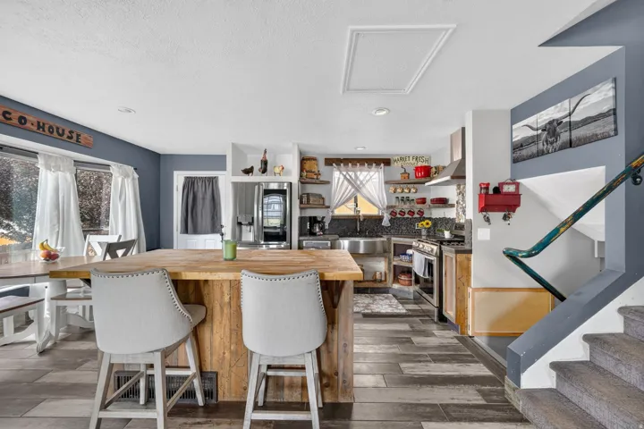 Expansive kitchen island with a wood countertop, integrated stainless steel appliances, open shelving, and wood-finish flooring