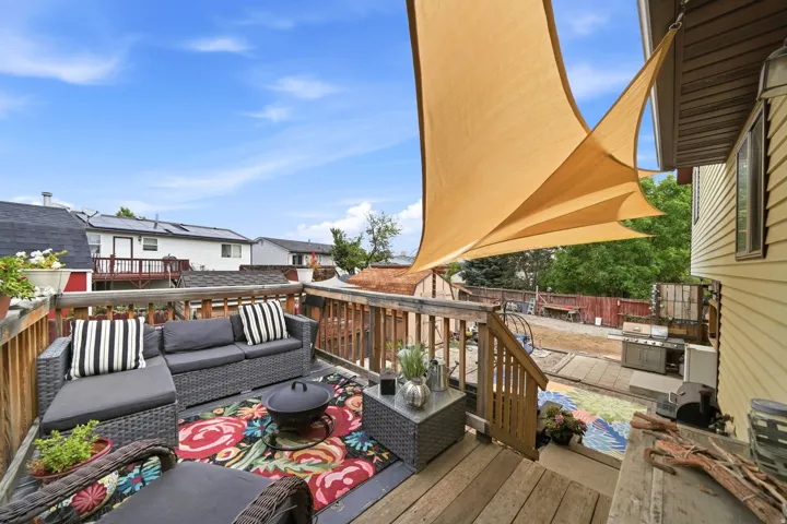 Expansive outdoor deck with wood railing, attached sunshade, and exterior siding