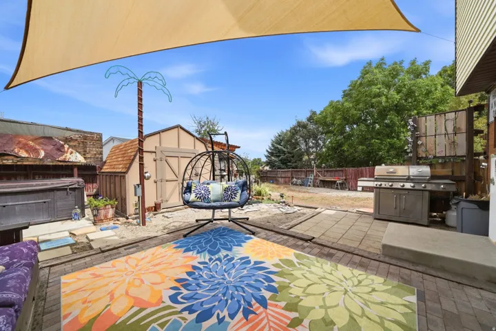 Outdoor living space featuring a shade sail, paver patio, storage shed, and a built-in outdoor grill station