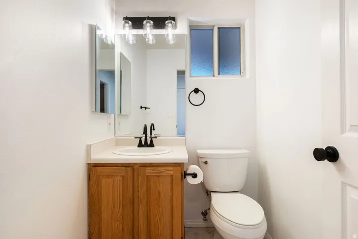 Vanity with wood-finish cabinetry, black fixtures, wall-mounted mirror, and frosted window