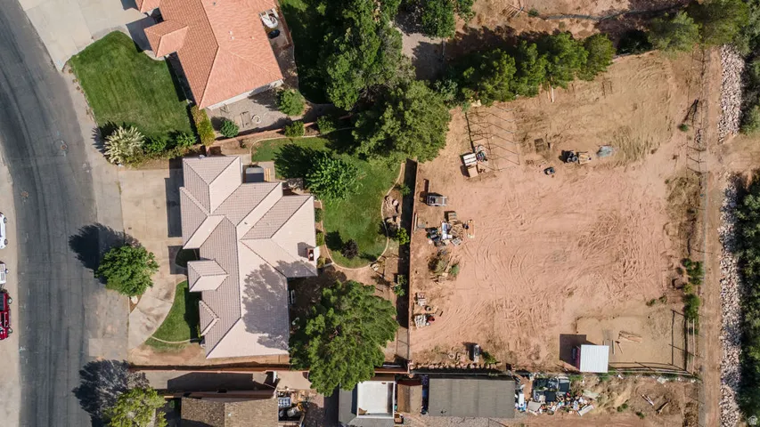 Expansive property featuring a multi-gabled roofline, mature trees, manicured lawn areas, and a large undeveloped parcel