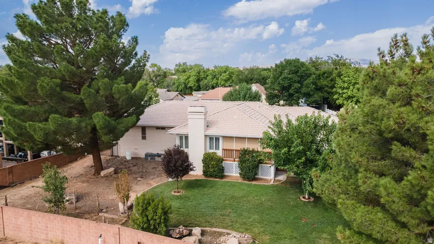Expansive backyard featuring a manicured lawn, mature trees, a composite deck, and a tiled roof