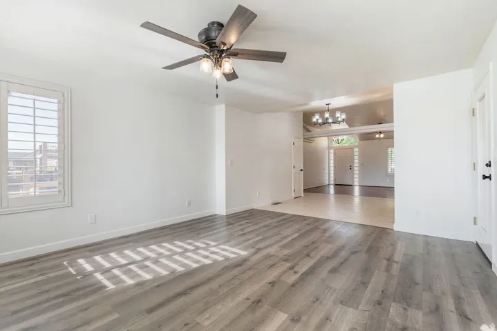 Wood-finish flooring, plantation shutters, contemporary ceiling fan, recessed lighting, and a multi-fixture chandelier