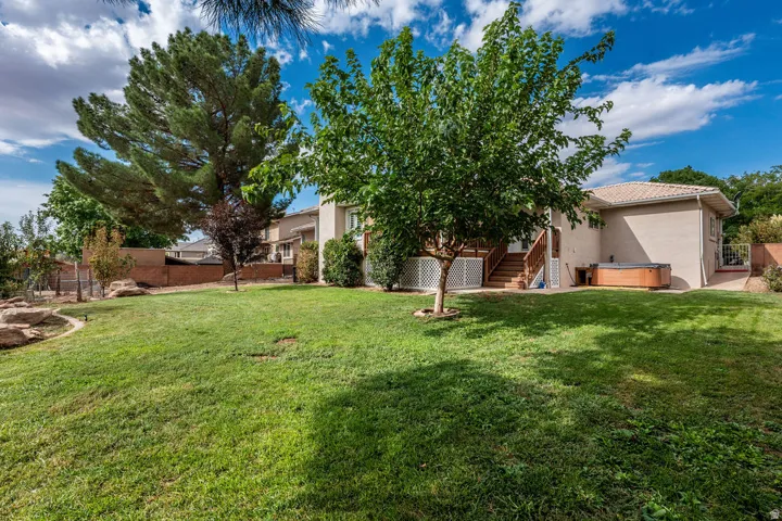Expansive backyard featuring a large lawn, mature trees, and a built-in hot tub