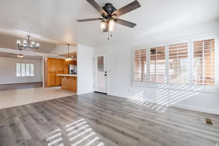 Wood-finish flooring, plantation shutters, ceiling fan with integrated lighting, recessed lighting, and kitchen with wood cabinetry