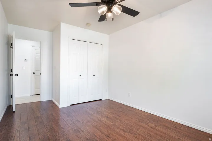 Wood-finish flooring, white walls, and a ceiling fan with integrated lighting
