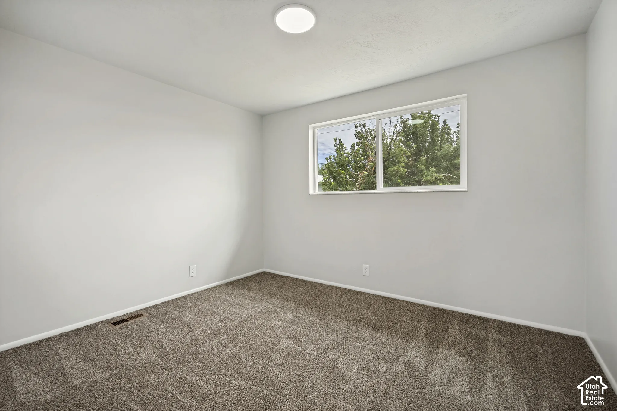 Recessed ceiling light fixture, neutral wall paint, carpeted flooring, and a large window