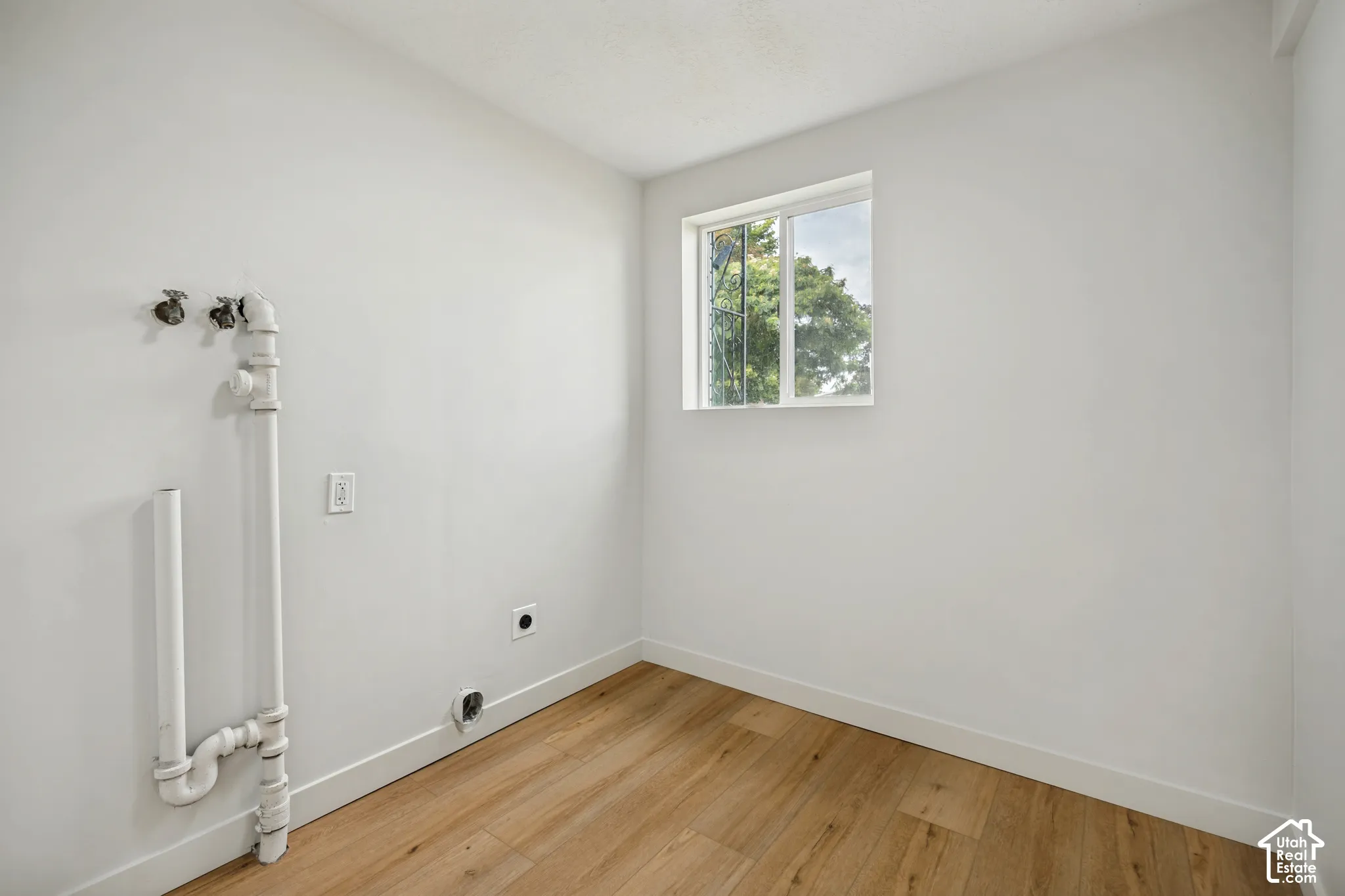 Light wood-finish flooring, white walls, and a single window with a white frame