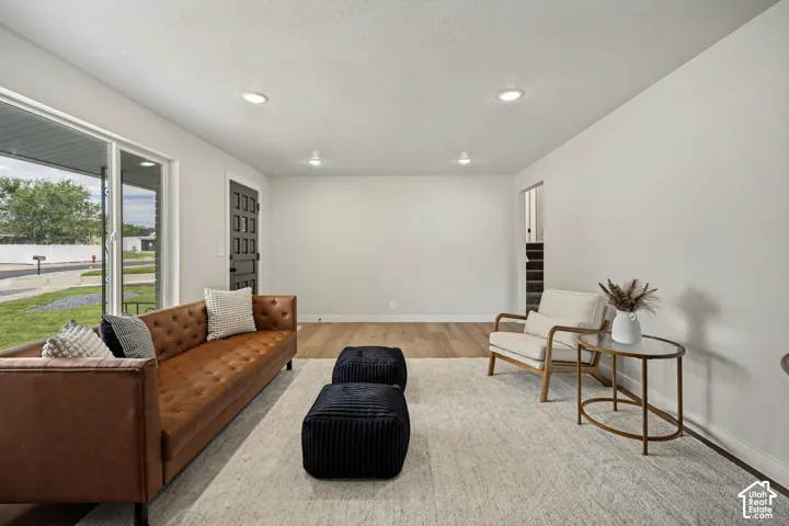 Recessed lighting, wood-finish flooring, white wall finishes, and a dark paneled door