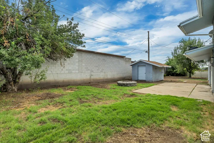 Spacious backyard with mature landscaping and established trees, concrete patio, detached storage shed, and open lawn area ideal for outdoor use and expansion potential