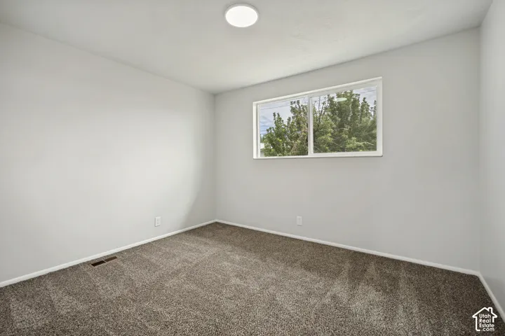Recessed ceiling light fixture, neutral wall paint, carpeted flooring, and a large window