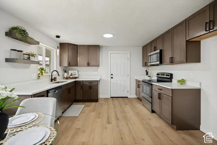 Wood-finish flooring, white countertops, dark wood-tone cabinetry, stainless steel appliances, and a recessed ceiling light