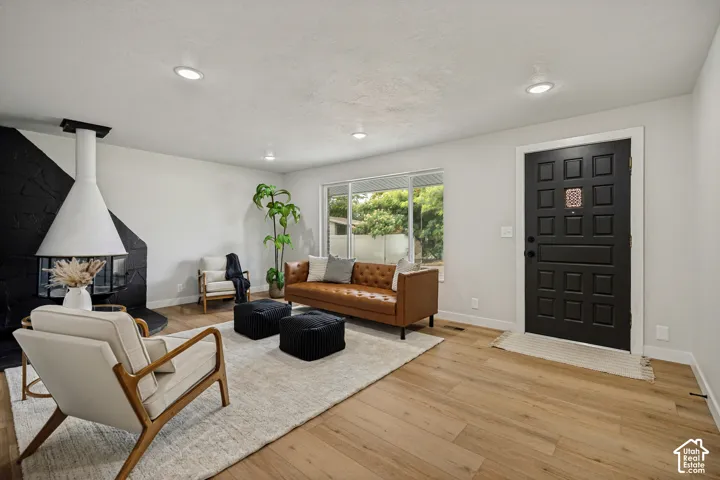 Wood-finish flooring, recessed lighting, expansive windows, and a black and white accent wall with a built-in fireplace