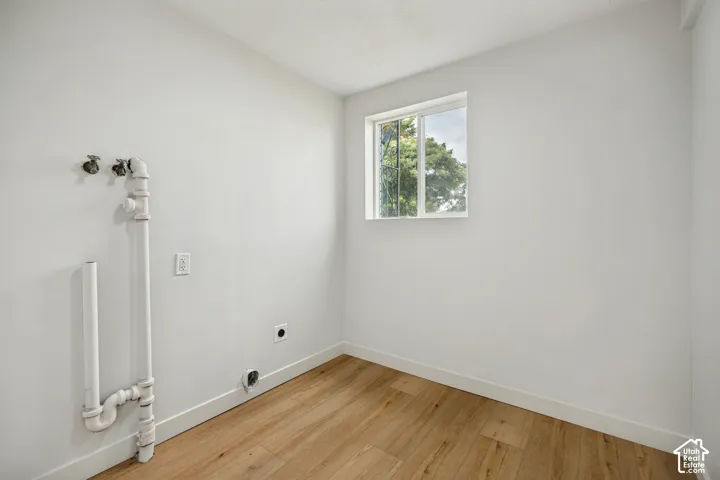 Light wood-finish flooring, white walls, and a single window with a white frame
