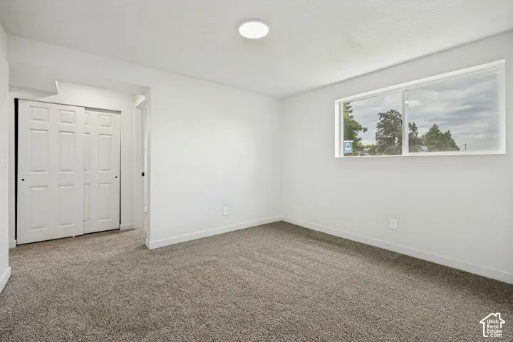 Recessed ceiling light fixture, neutral wall paint, gray carpeting, horizontal window, and bi-fold closet doors