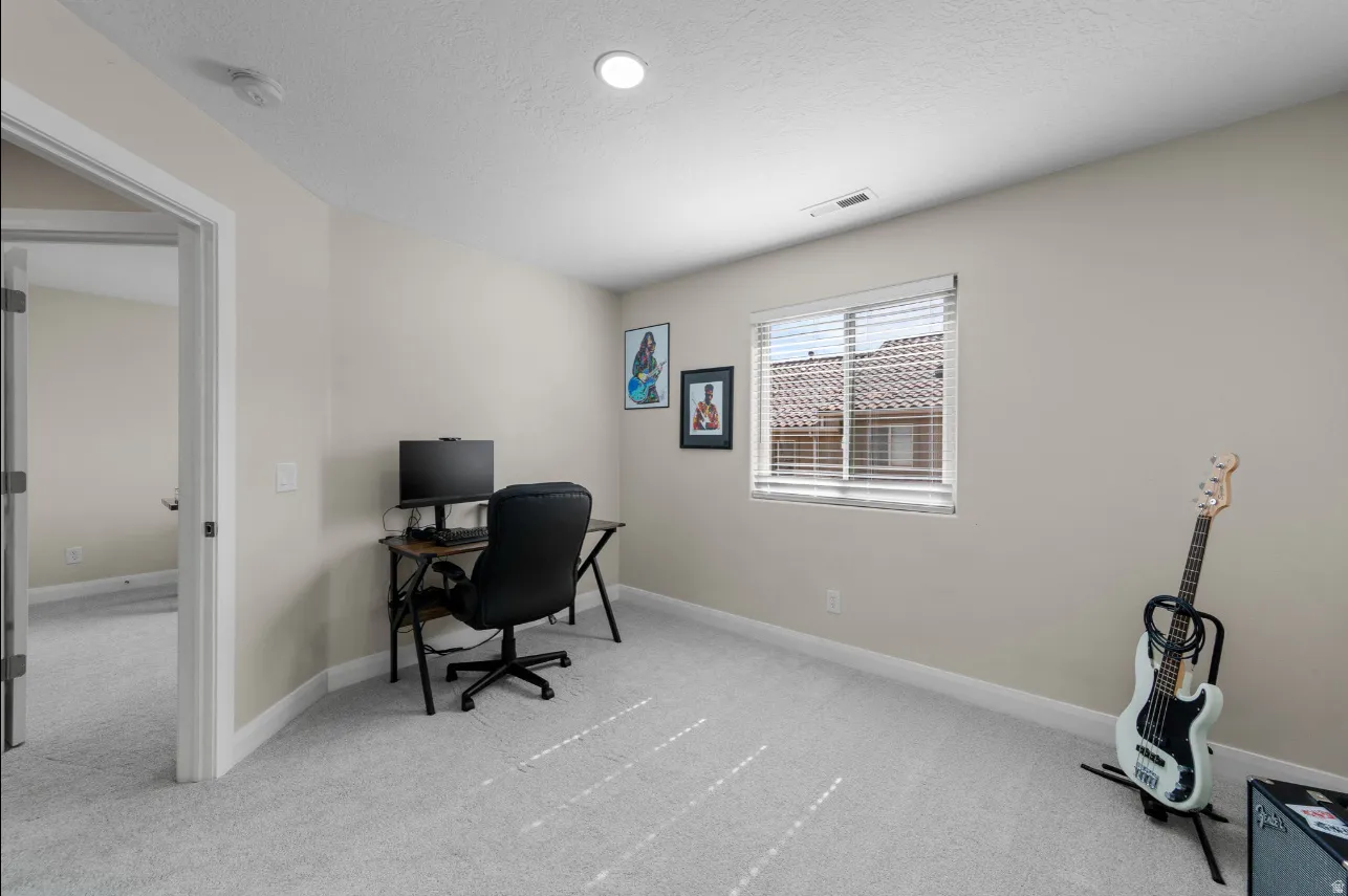 Neutral wall paint color, recessed ceiling lighting, light gray carpeting, and a window with blinds