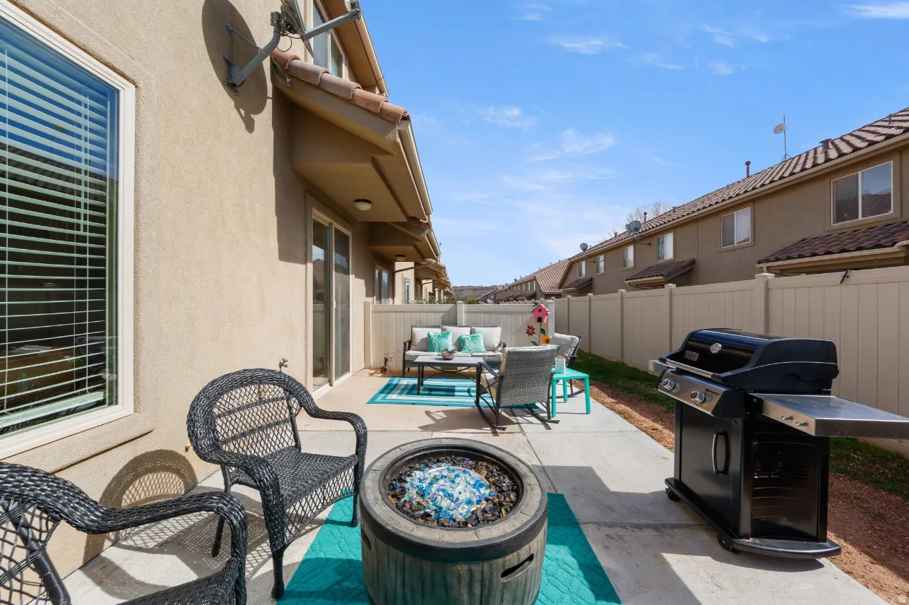 Paved outdoor patio with a built-in fire pit, privacy fencing, and exterior stucco finish