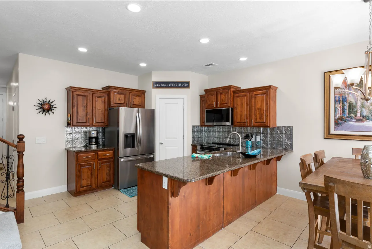Kitchen featuring recessed lighting, wood cabinetry, stainless steel appliances, and a tiled backsplash