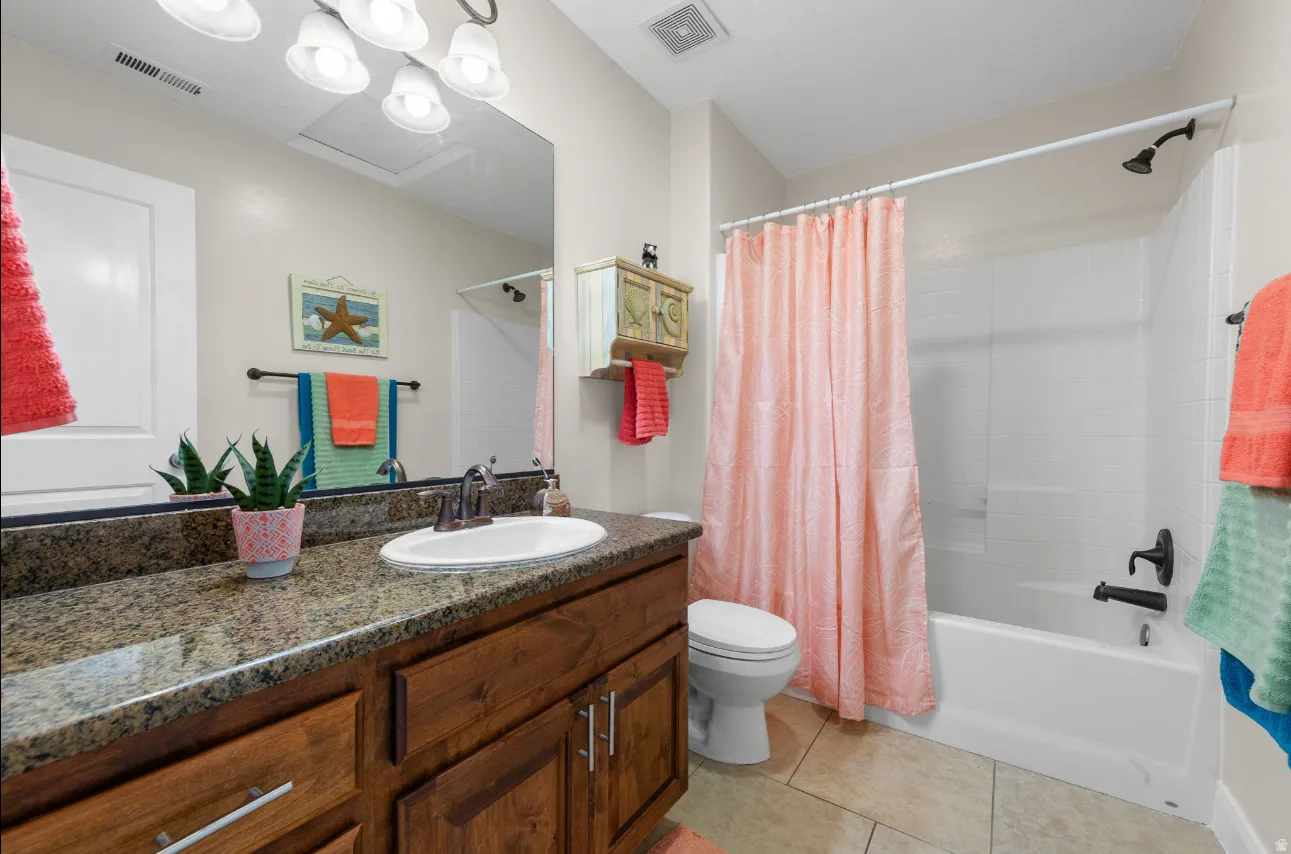 Bathroom featuring a single vanity with stone-finish countertop, wood-finish cabinetry, and an integrated sink