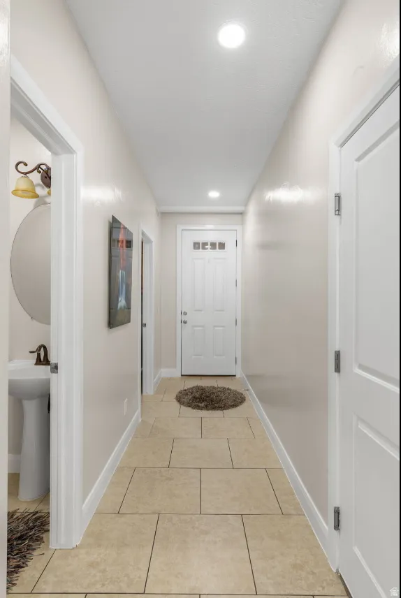 Recessed lighting, tile flooring, white interior doors, and a pedestal sink with a wall-mounted mirror