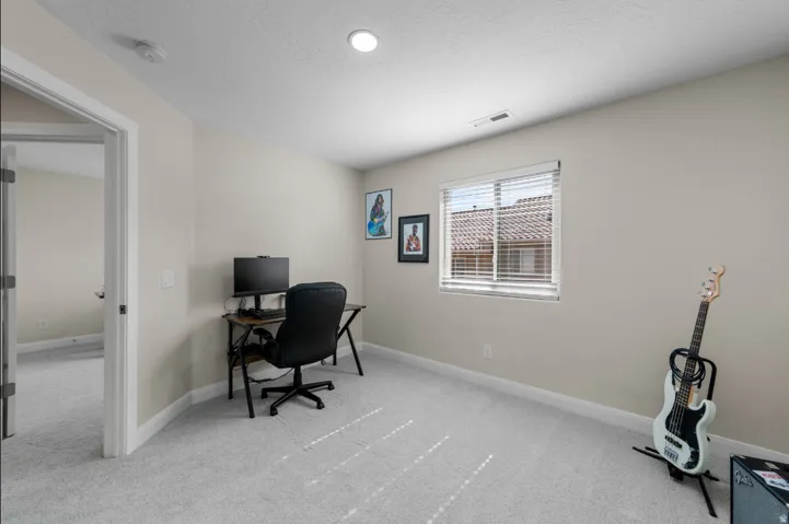 Neutral wall paint color, recessed ceiling lighting, light gray carpeting, and a window with blinds