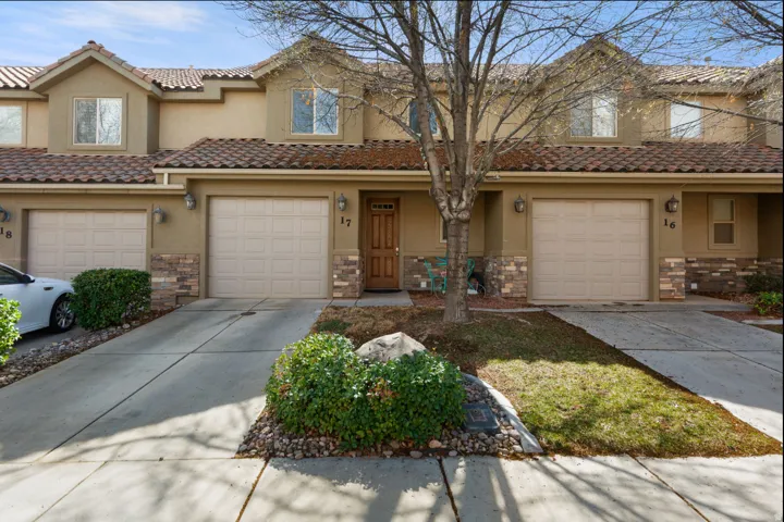 Stucco exterior with stone accents, concrete driveway, attached garage, tile roof, and a wood-finish entry door