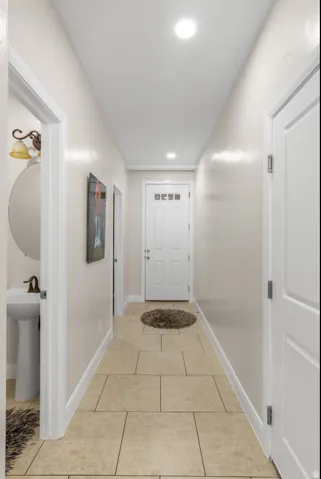 Recessed lighting, tile flooring, white interior doors, and a pedestal sink with a wall-mounted mirror